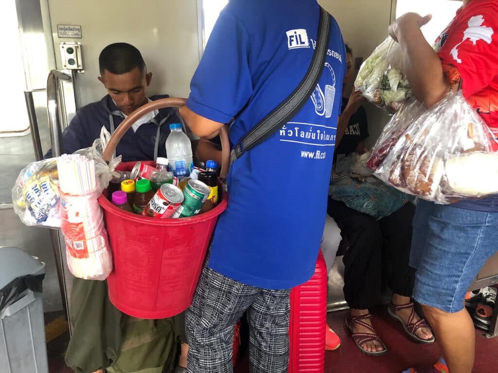 Local sellers offering food and drinks on the train in Thailand