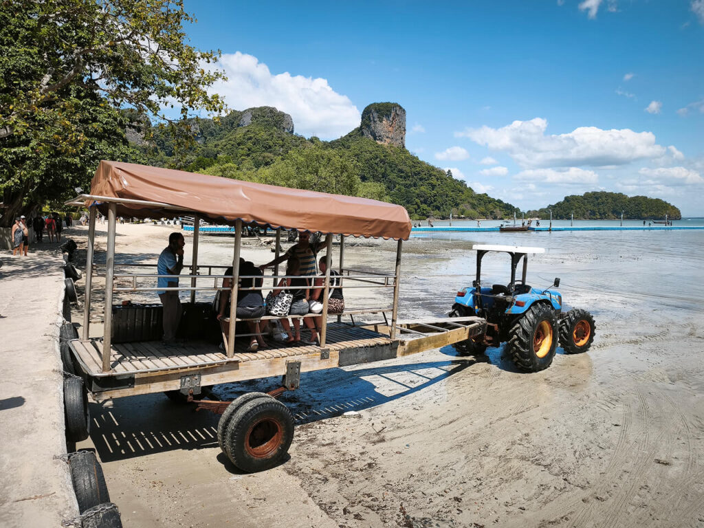 East Railay Beach at low tide with tourists transported to boats by tractor
