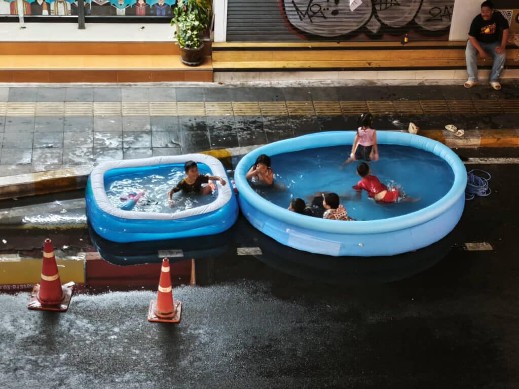 Children swim in an inflatable pool outside during Songkran.