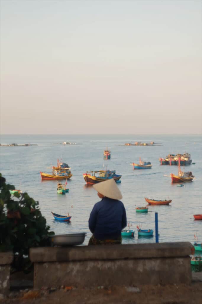 Vietnamese woman sitting near the sea with a hat