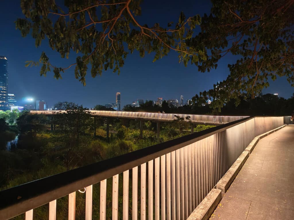 Illuminated skywalk at Benchakitti Park in the evening